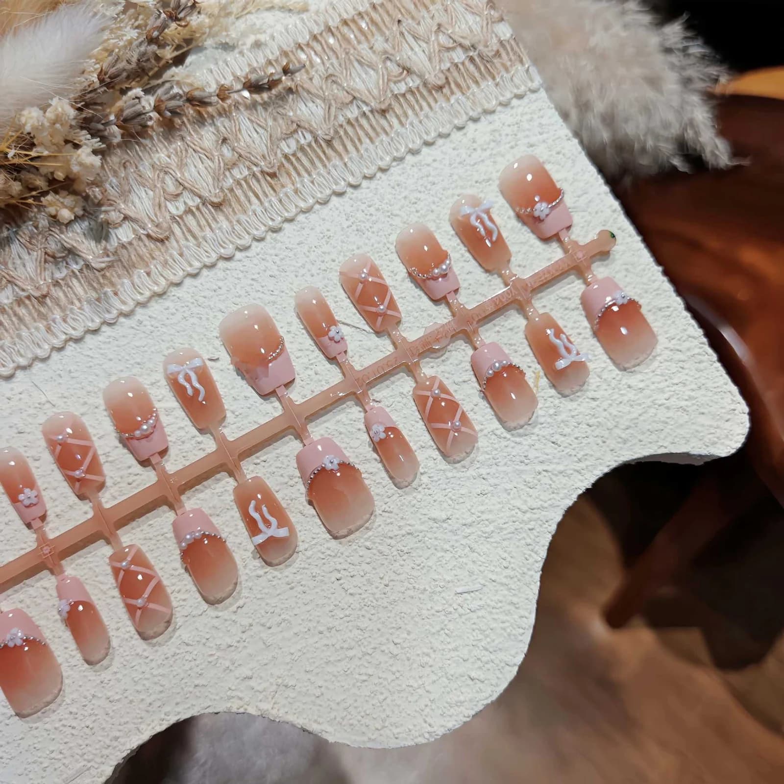 Rosa French-Tip-Kunstnägel mit Schleife und Kette, kurz quadratisch